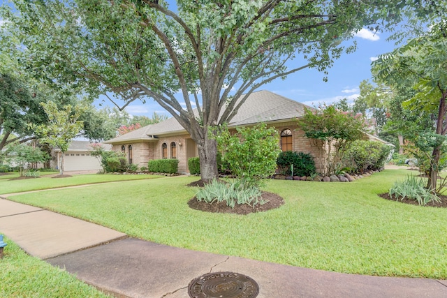 view of front of house featuring a front lawn, an attached garage, and brick siding