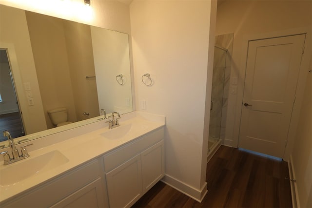 bathroom with hardwood / wood-style flooring, toilet, vanity, and an enclosed shower