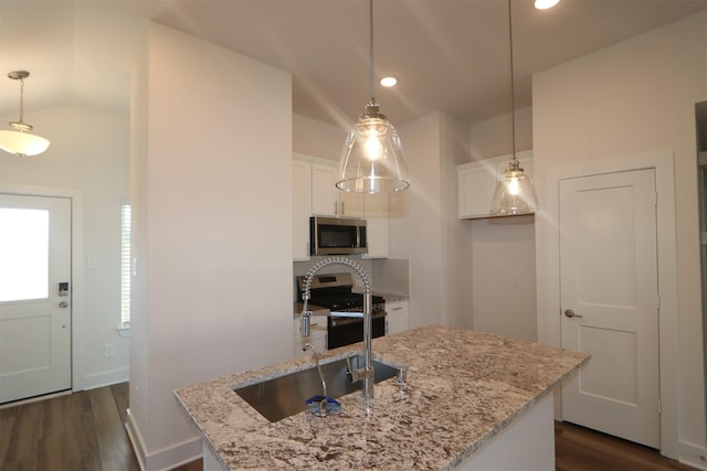 kitchen with a center island with sink, pendant lighting, sink, appliances with stainless steel finishes, and white cabinets