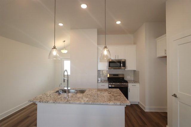 kitchen featuring stainless steel appliances, hanging light fixtures, and an island with sink