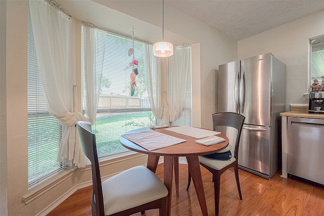 dining space with a wealth of natural light, light wood-type flooring, and a textured ceiling