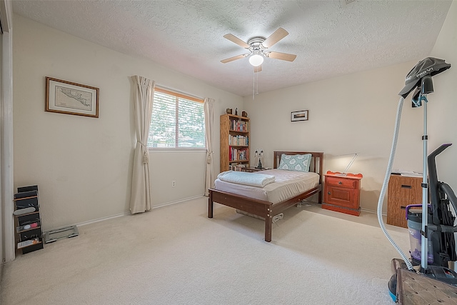 bedroom with ceiling fan, light colored carpet, and a textured ceiling