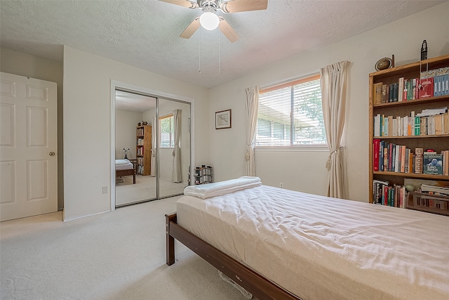 carpeted bedroom featuring ceiling fan, a closet, and a textured ceiling