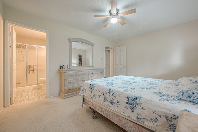 bedroom with ceiling fan, ensuite bathroom, light colored carpet, and a textured ceiling