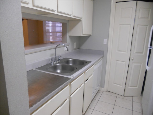 kitchen featuring refrigerator, light tile patterned floors, white dishwasher, sink, and white cabinets