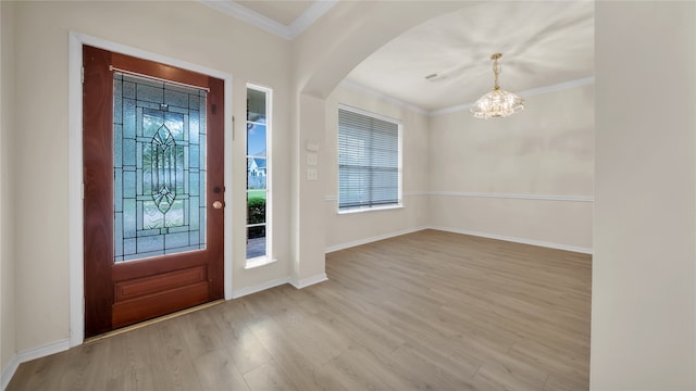 entryway with ornamental molding, a notable chandelier, and light hardwood / wood-style flooring