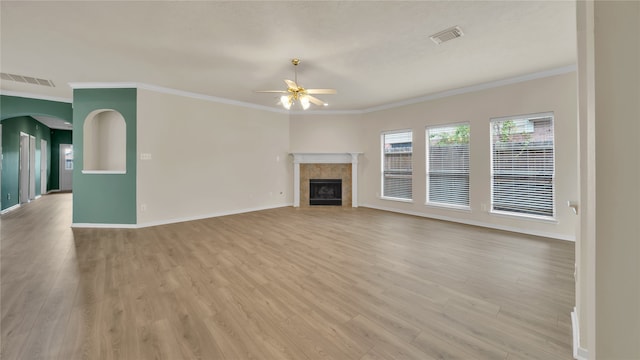 unfurnished living room with ceiling fan, ornamental molding, a tile fireplace, and light hardwood / wood-style floors