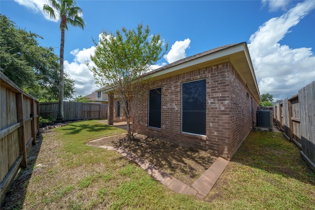 back of house with central AC unit and a yard