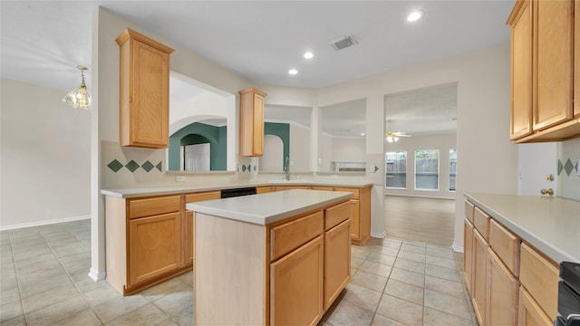 kitchen featuring ceiling fan with notable chandelier, backsplash, decorative light fixtures, light brown cabinetry, and a center island