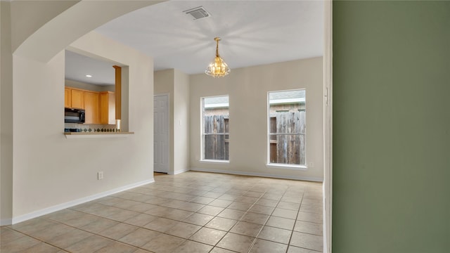 tiled empty room with a notable chandelier