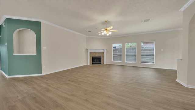 unfurnished living room with a tiled fireplace, crown molding, hardwood / wood-style floors, and ceiling fan