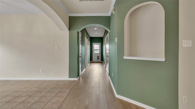 corridor with ornamental molding and light hardwood / wood-style floors