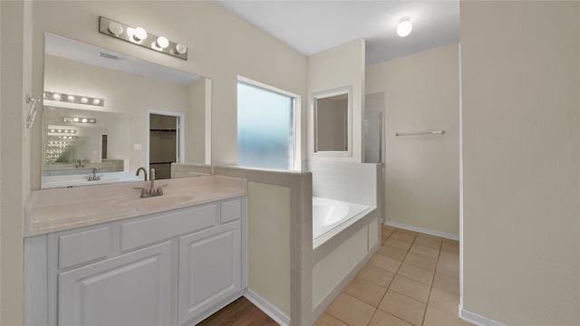 bathroom with vanity, tile patterned flooring, and tiled bath