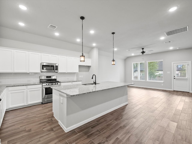 kitchen featuring an island with sink, stainless steel appliances, dark wood-type flooring, and white cabinetry