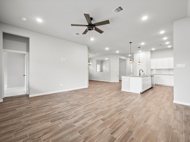 unfurnished living room featuring light wood-type flooring, sink, and ceiling fan