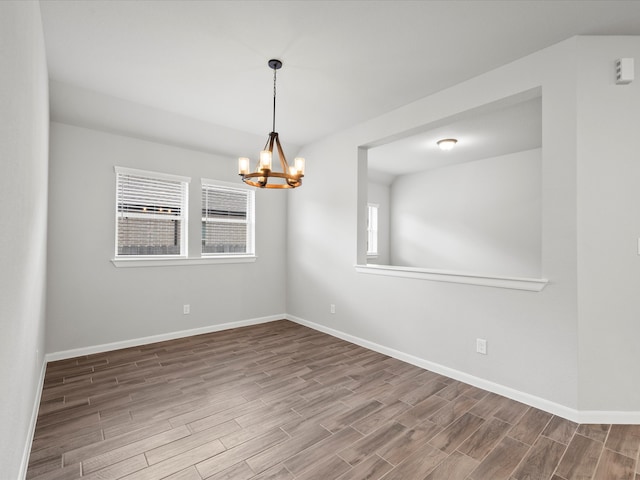 spare room featuring a notable chandelier, plenty of natural light, and hardwood / wood-style floors