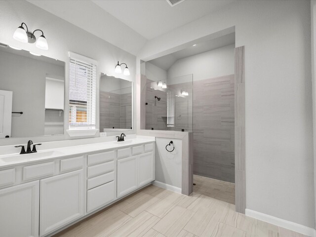 bathroom featuring a tile shower, vaulted ceiling, and vanity