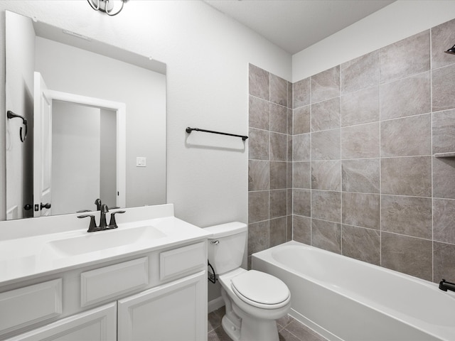 full bathroom with tile patterned flooring, tiled shower / bath, vanity, and toilet