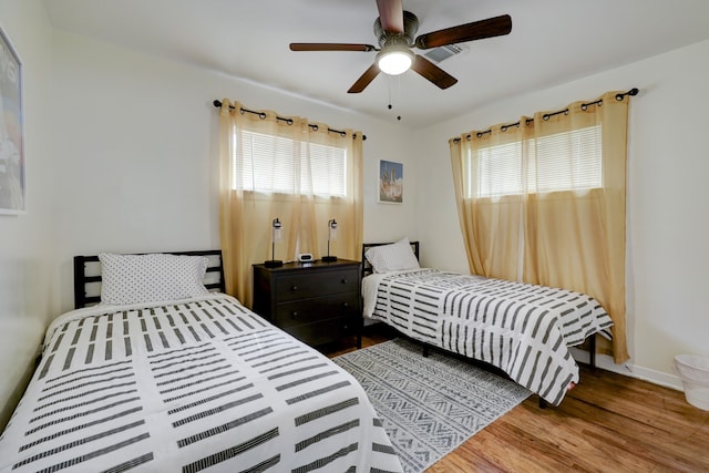 bedroom with ceiling fan, hardwood / wood-style floors, and multiple windows