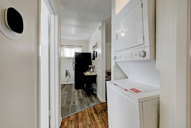 laundry area featuring stacked washing maching and dryer and dark hardwood / wood-style floors