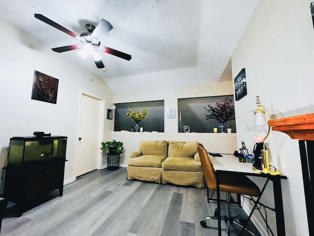 living area featuring a ceiling fan, lofted ceiling, wood finished floors, and baseboards