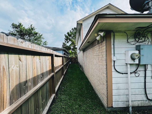 view of side of property with a fenced backyard and brick siding