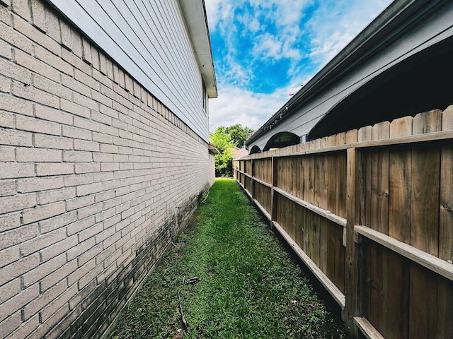 view of property exterior with brick siding and fence