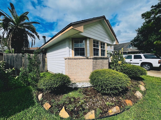 view of home's exterior featuring brick siding and fence