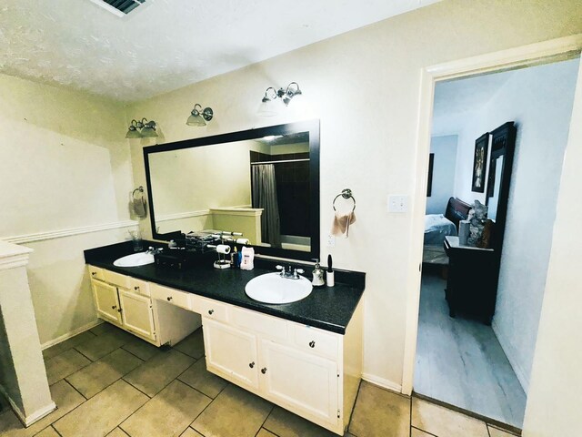 ensuite bathroom featuring double vanity, tile patterned flooring, ensuite bathroom, and a sink