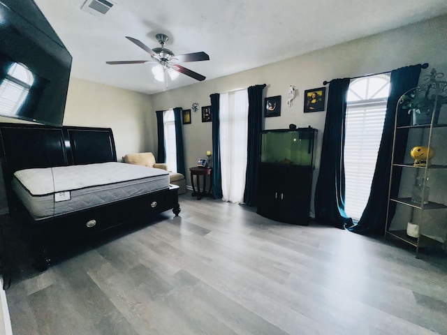 bedroom with multiple windows, ceiling fan, and wood-type flooring