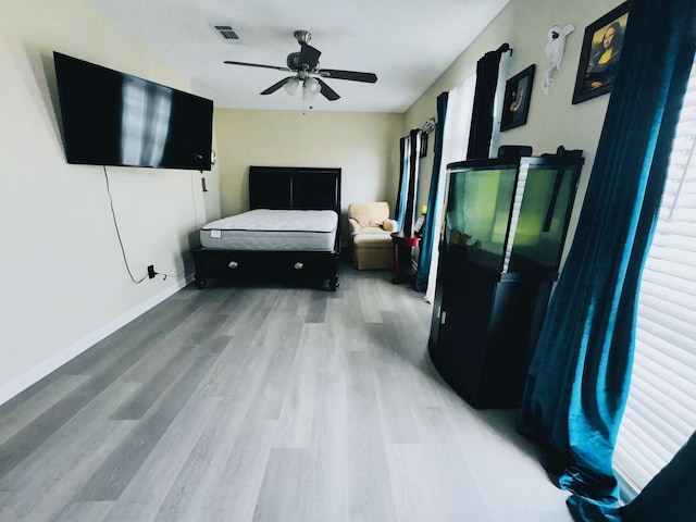 bedroom featuring light wood-type flooring, visible vents, baseboards, and ceiling fan