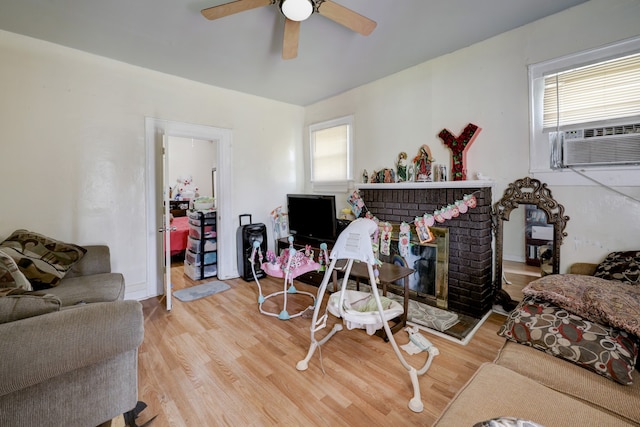 living room featuring cooling unit, ceiling fan, a fireplace, and light hardwood / wood-style flooring