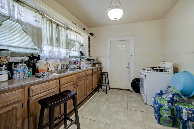 kitchen featuring hanging light fixtures, light tile patterned floors, white gas stove, and sink