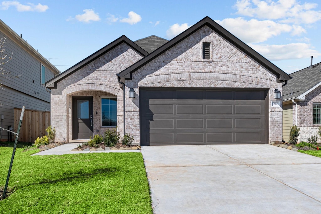 french provincial home with brick siding, concrete driveway, a front yard, fence, and a garage