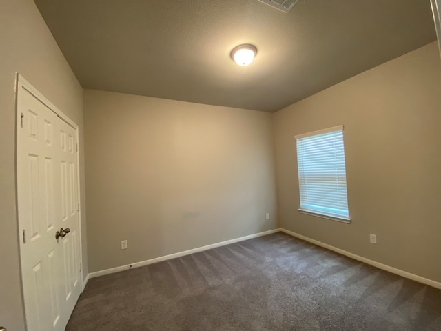 unfurnished room featuring dark colored carpet