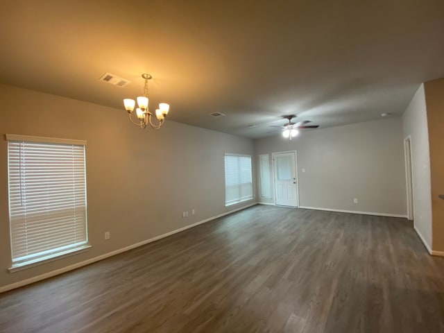 empty room featuring ceiling fan with notable chandelier and dark hardwood / wood-style floors