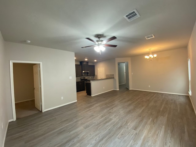 unfurnished living room with ceiling fan with notable chandelier and dark hardwood / wood-style floors