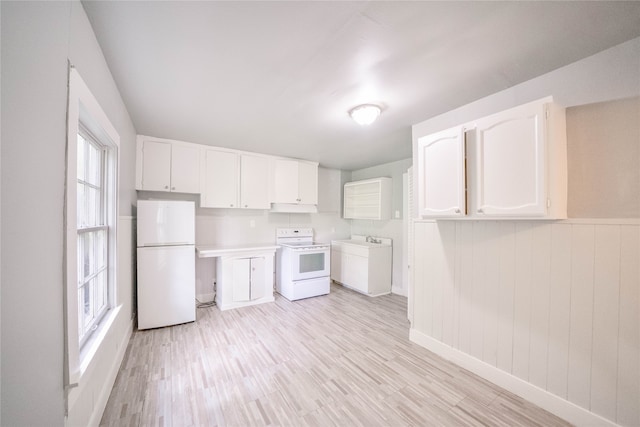 kitchen with white appliances, light hardwood / wood-style flooring, wood walls, and white cabinets