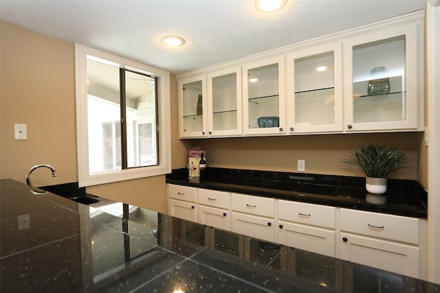 kitchen featuring a textured ceiling, sink, and white cabinets