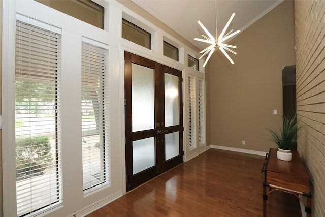 doorway with ornamental molding, dark wood-type flooring, french doors, and an inviting chandelier