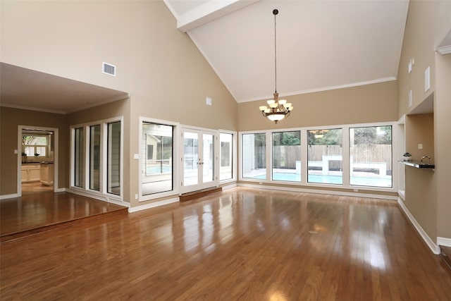 spare room featuring dark wood-type flooring, high vaulted ceiling, a wealth of natural light, and a chandelier