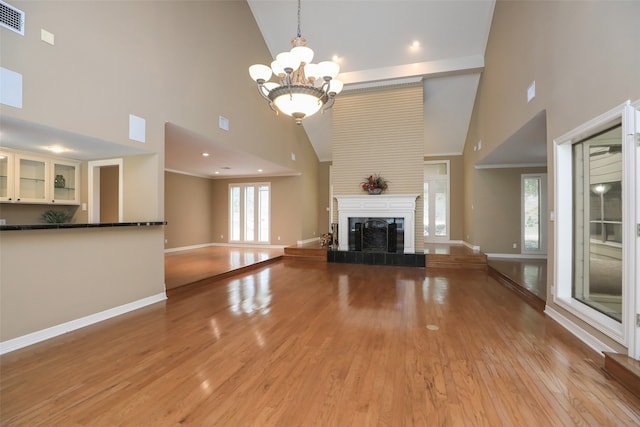 unfurnished living room featuring high vaulted ceiling, an inviting chandelier, and light hardwood / wood-style flooring