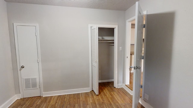 unfurnished bedroom with a textured ceiling and light hardwood / wood-style flooring