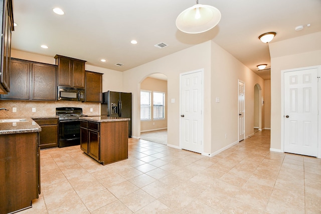 kitchen with a center island, stone counters, sink, black appliances, and tasteful backsplash