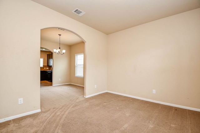 spare room featuring a notable chandelier and carpet floors