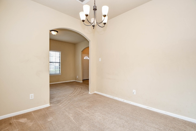 carpeted empty room with a chandelier