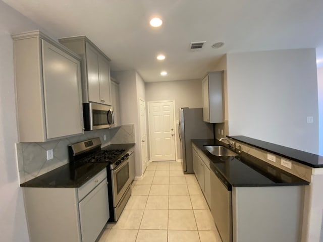 kitchen featuring appliances with stainless steel finishes, backsplash, gray cabinetry, sink, and light tile patterned floors