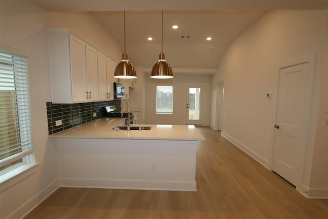 kitchen with sink, decorative backsplash, white cabinets, decorative light fixtures, and kitchen peninsula