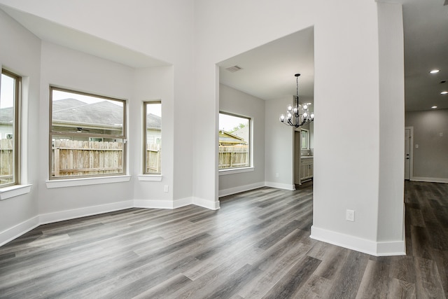 unfurnished living room featuring an inviting chandelier and hardwood / wood-style flooring