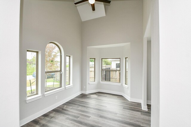 unfurnished room with ceiling fan, high vaulted ceiling, and hardwood / wood-style flooring